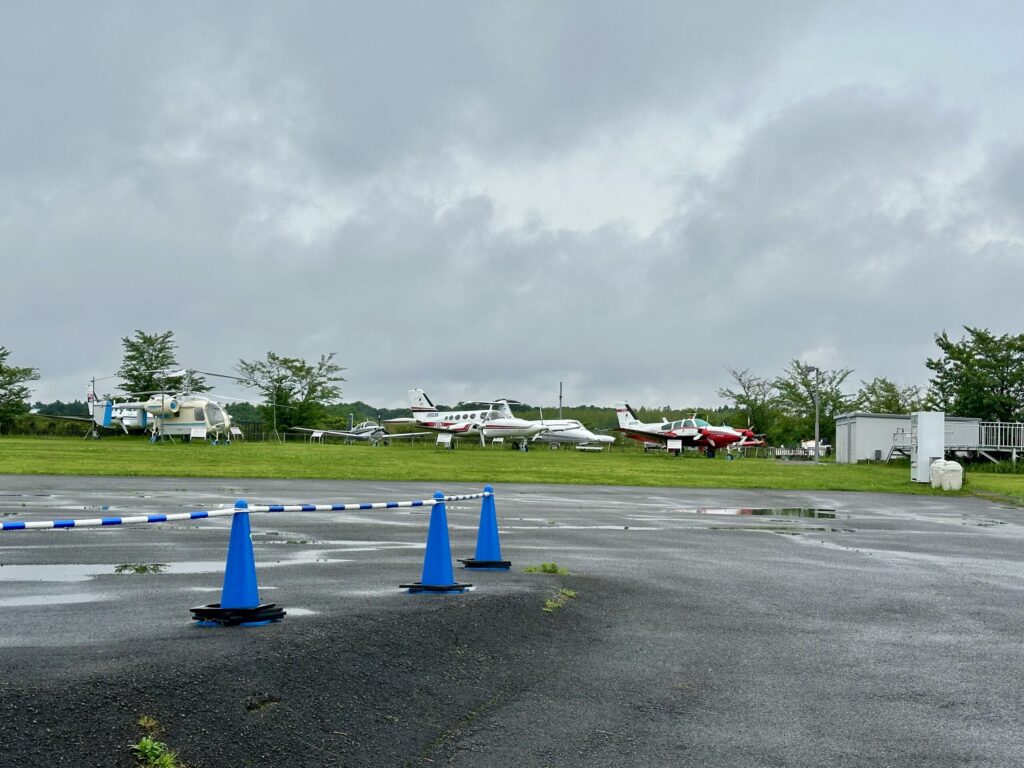 屋外展示場の芝生に並ぶセスナやヘリコプターなどの小型機
