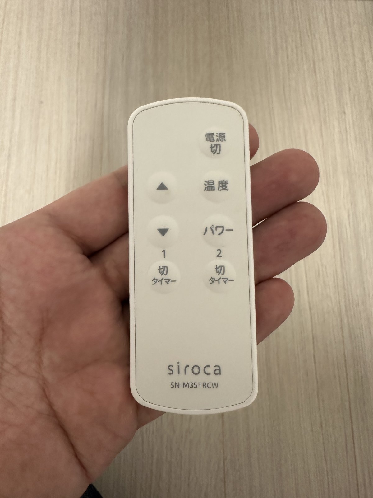 かるポカのリモコンを手に持ったところ。電源切・温度・パワー・上下・切タイマーのボタンが並ぶ