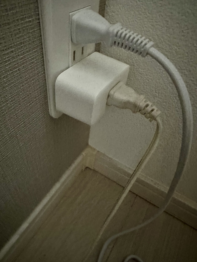 寝室のコンセントに挿したSwitchBotプラグミニに、見守りカメラの電源プラグをつないでいる