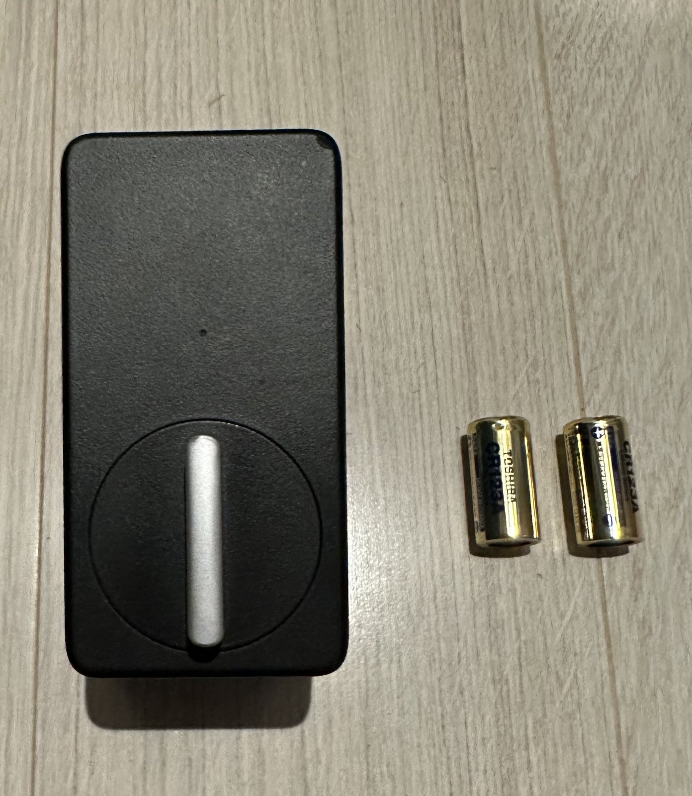 買い替え前に使っていたSwitchBotロック(従来モデル)の本体と、交換用のCR123Aリチウム電池2本
